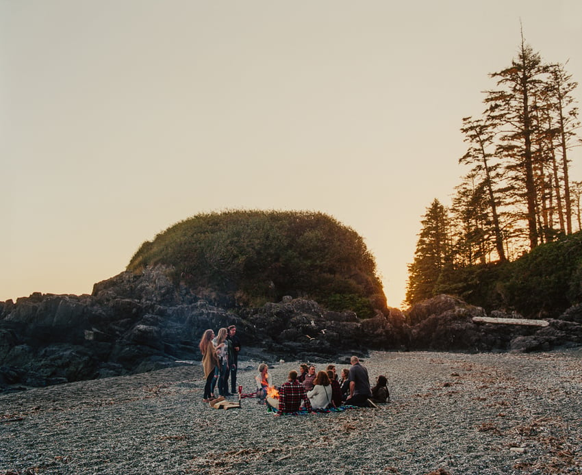 A photo of a group of friends or family gathers for an intimate dinner in the midst of the wilderness. Photo by Kamil Bialous.