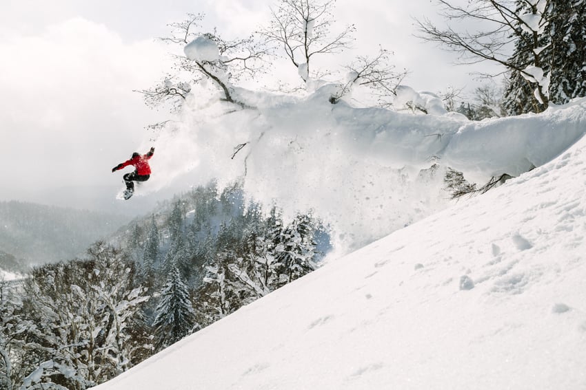 A person snowboarding at a high altitude photographed by Adam Moran.