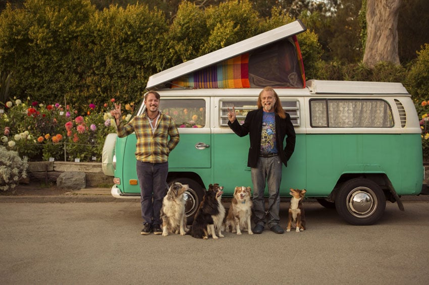 Two companions striking a pose in front of their camper with a pack of dogs. Photo by Kris Davidson.