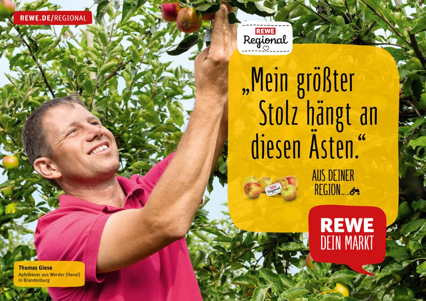 Markus Altmann's photo for a Rewe ad campaign featuring a smiling man in a red collared shirt reaching up to pick an apple from a tree.