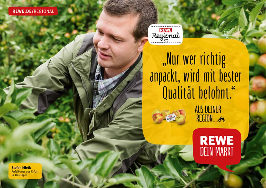 Markus Altmann's photo for a Rewe ad campaign featuring a smiling man in a green jacket reaching into an apple tree's branches.
