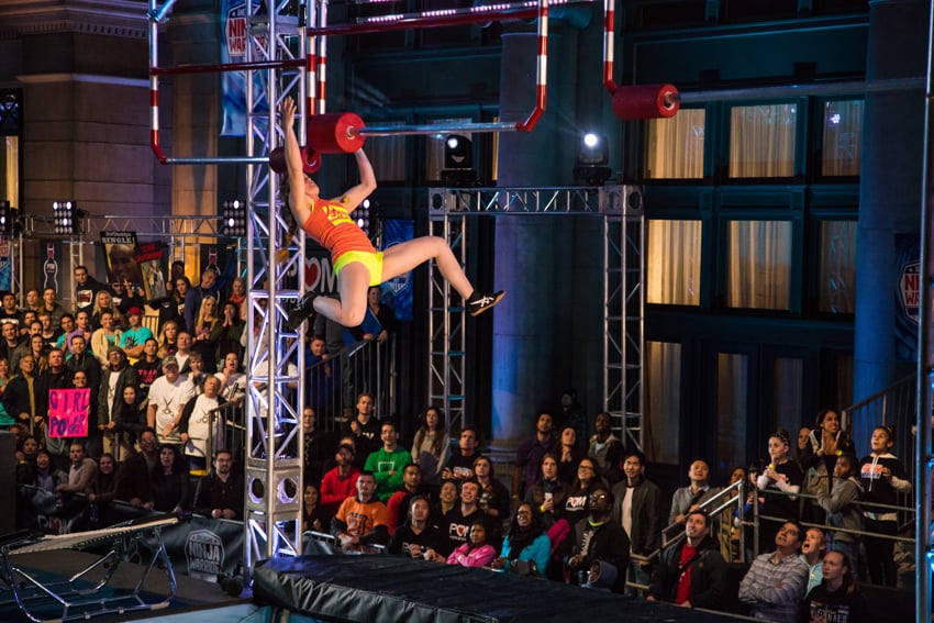 A Ninja Warrior contestant is captured in the middle of a performance, navigating a challenging course with incredible agility and determination. Photo by Rocco Ceselin.