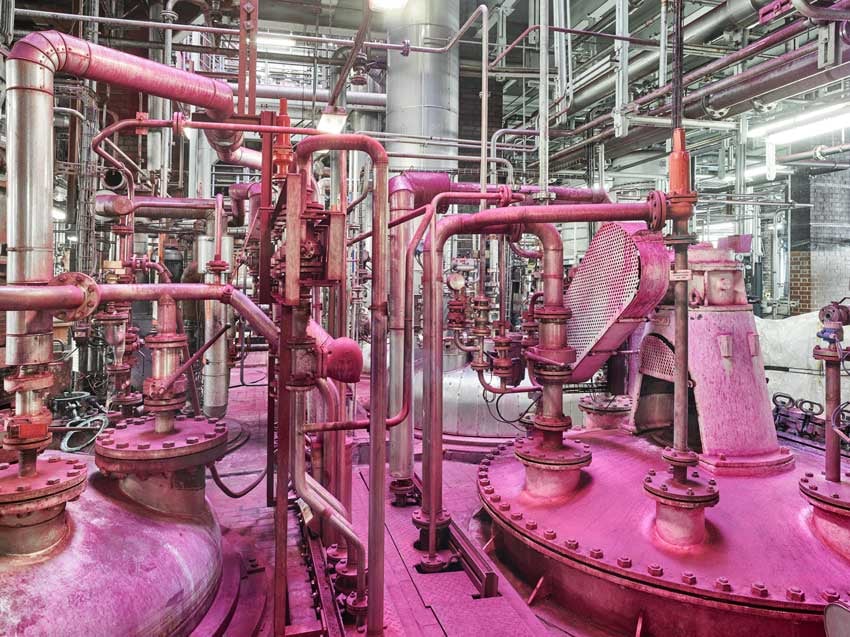 The photographic duo Scanderbeg Sauer's photo of the inside of an industrial factory. The photo features a large and complicated-looking network of metal pipes of various sizes. The pipes in the foreground have an interesting hot pink hue, while those in the background are a bright chrome.
