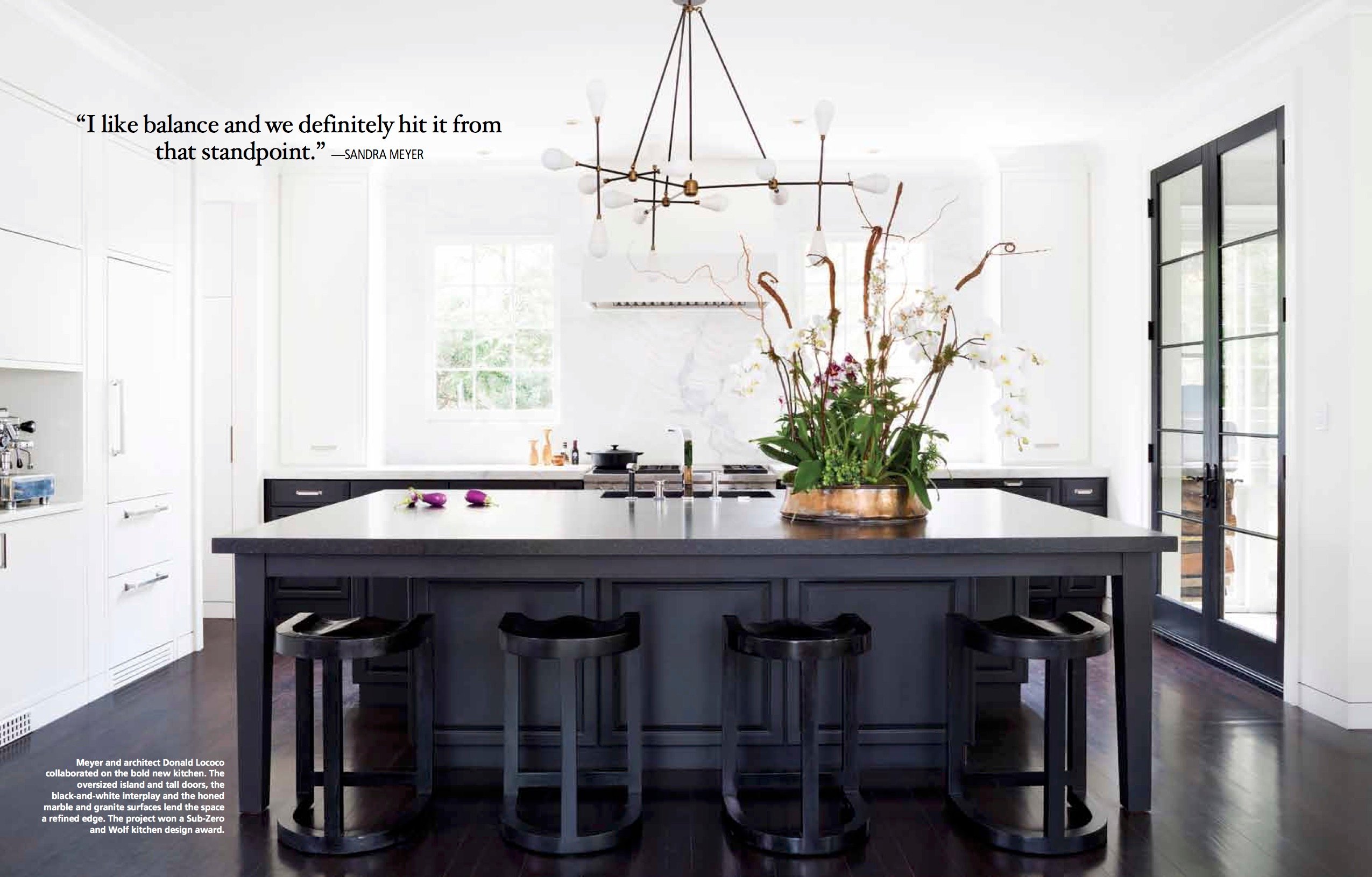 A tear sheet from Home & Design showcasing a kitchen interior with a kitchen island with flowers on top of it. Photo by Stacy Zarin Goldberg,