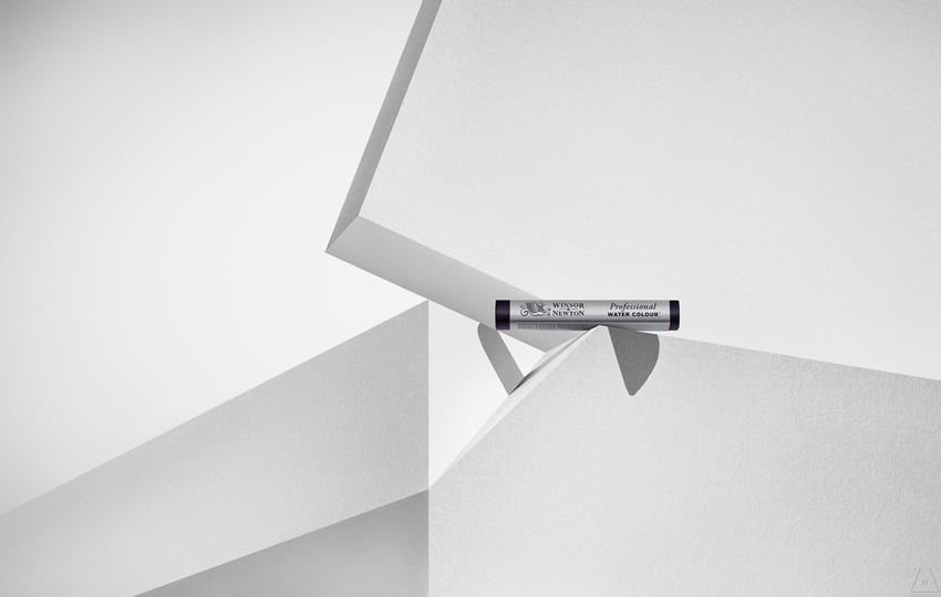 Timothy Hogan's photo for Winsor & Newton featuring a their Professional Water Colour product, which is small and cylindrical. It balances on the edge of a white plinth and casts a shadow.