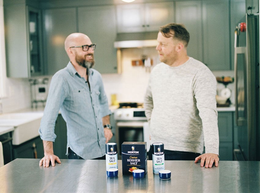Two men engaged in conversation, framed by the presence of a strategically placed carton of salt. Photo by Abigail Bobo.