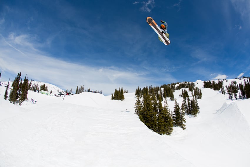 Photographer Adam Moran's photo for Mountain Dew. The photo features a person in the air on a snowboard. In the background is a snowy slope with a smattering of evergreen trees and a few people.