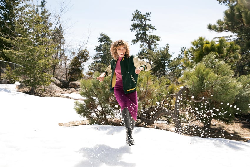 A woman running through snow in nature, photo by Amber Fouts.