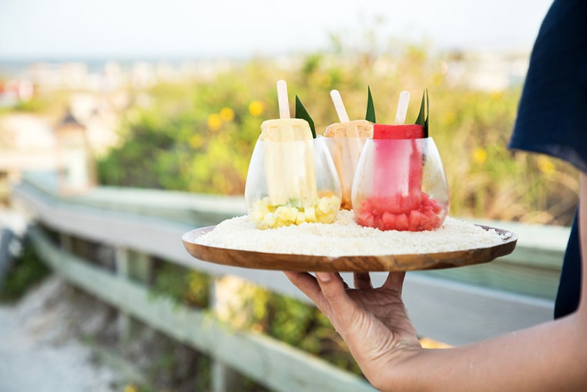 A waiter carrying a tray adorned with vibrant and exotic fruit drinks. Photo by Amy Mikler.