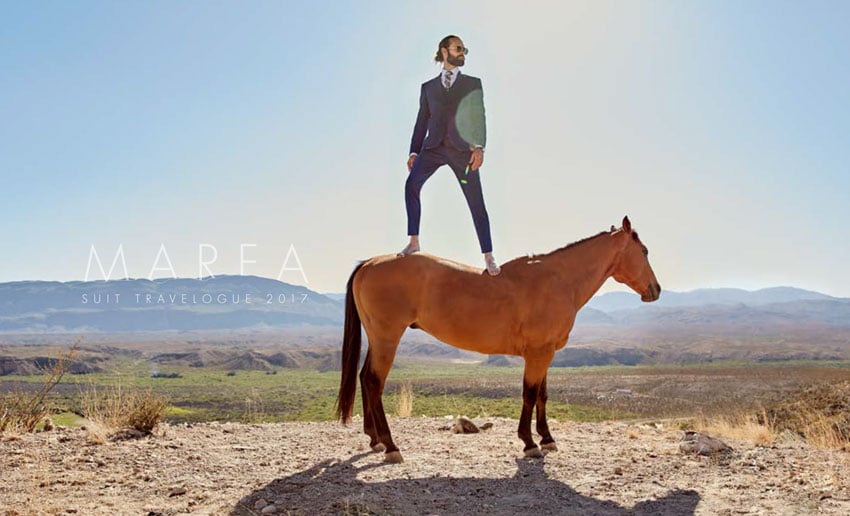 Tear sheet photo of a man wearing Marea suit while standing on a horse in a desert, photography by Andrew Klein.