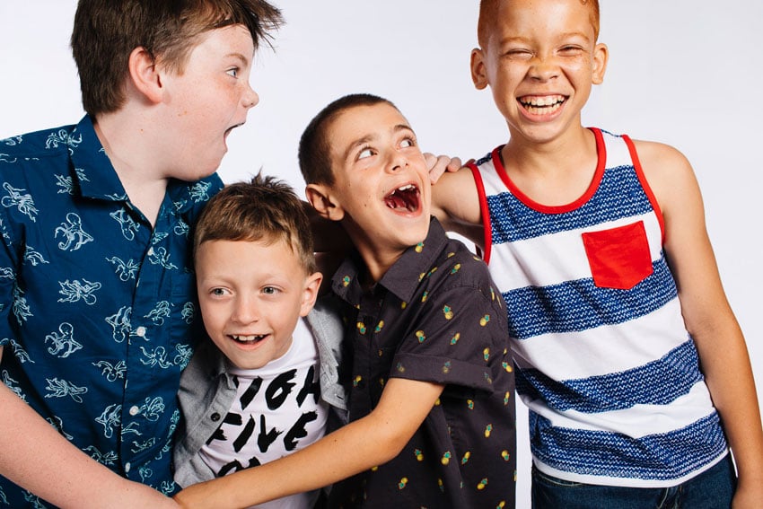 Photographer Caitie McCabe's studio image of four little boys of different heights playfully palling around while posing for the shot with arms around each other.