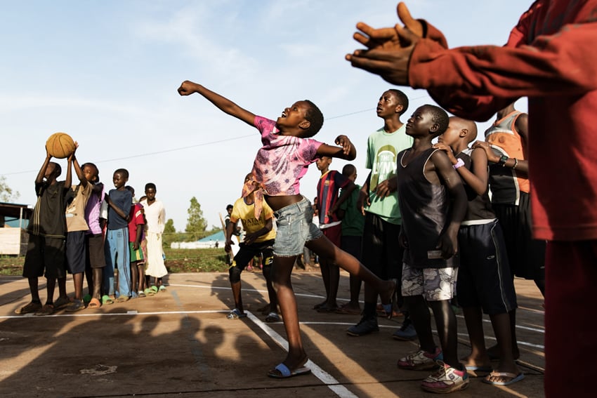 Energetic photo of children in Rwanda happily playing with a ball. Photo by Chris Cardoza.