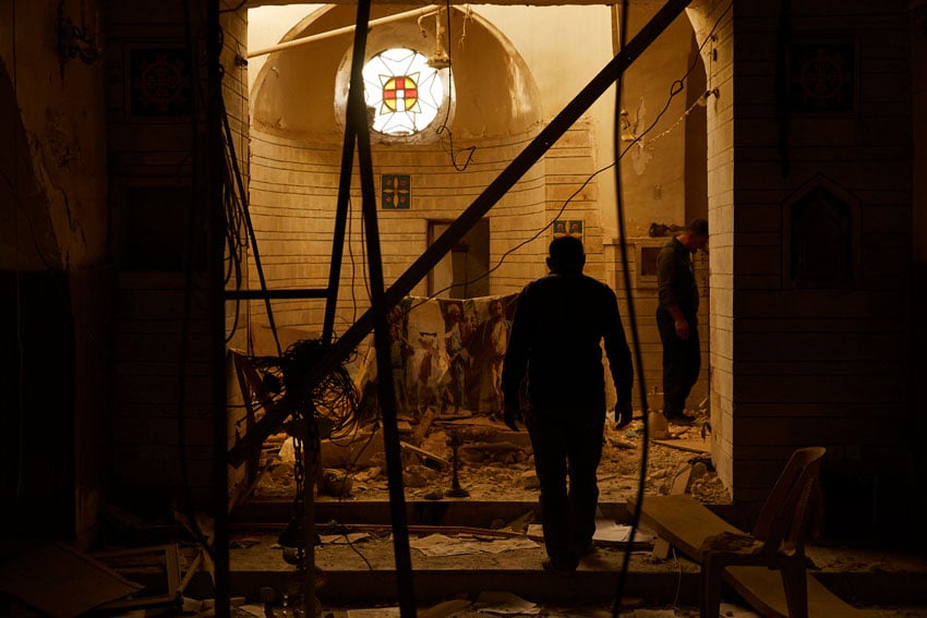 Men carefully exploring the interior of a church in ruins, photo by Clay Cook.