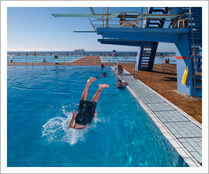 Image from web ad of someone diving headfirst into a pool with hands at their sides photographed by David Bloomer