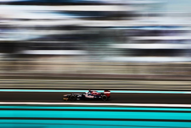 A race car driver going full speed, his surroundings a complete blur of color