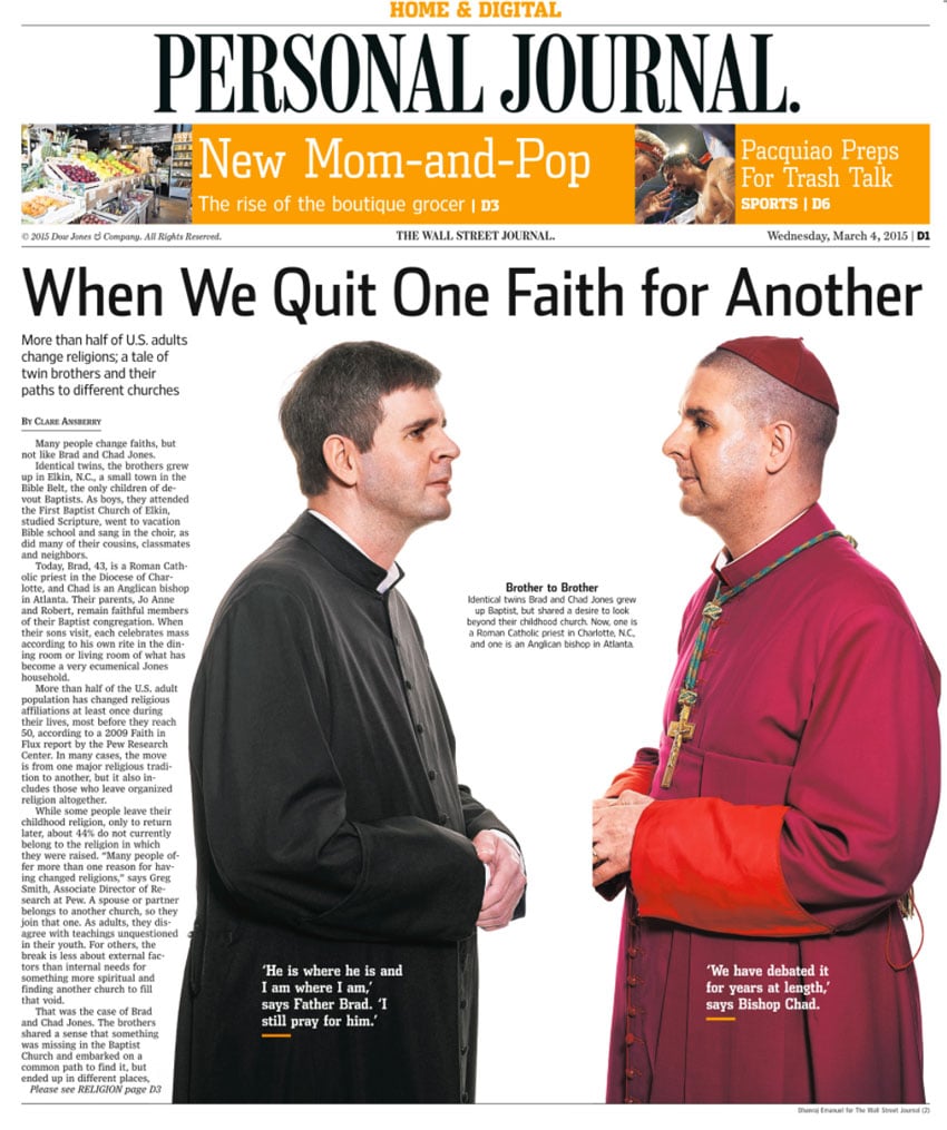 A tear sheet for The Wall Street Journal by photographer Dhanraj Emanuel. The tear sheet features two portraits of twin brothers Brad and Chad Jones. The portraits are separate, but face each other. The brother on the left wears a black clerical robe with a white layer underneath. The brother on the right wears a crimson clerical robe with a small crimson cap atop his buzzed hairstyle. He also wears a thick green lanyard with a large cross pendant. Both brothers have their hands clasped in front of them at waist height.