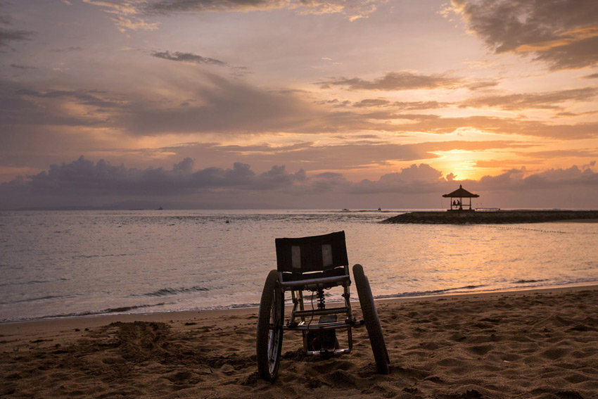 Ed Wray's photo of paraplegic surfer Bruno Hansen's wheelchair on the beach, silhouetted against the sunrise. The wheelchair facing out towards the ocean and is centered in the frame.