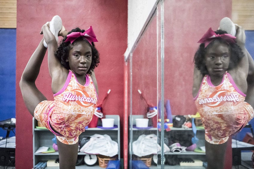 A young cheerleader stretches gracefully, showing dedication and focus before her performance.