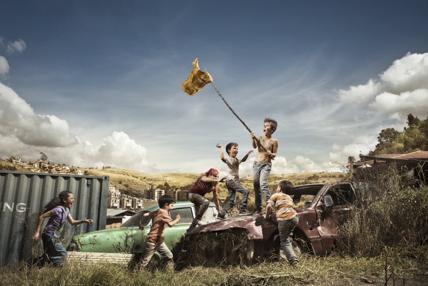 Several dirty kids reenacting battle scene waving flag overhead shot for Ad Photographers Worldwide by Cade Martin