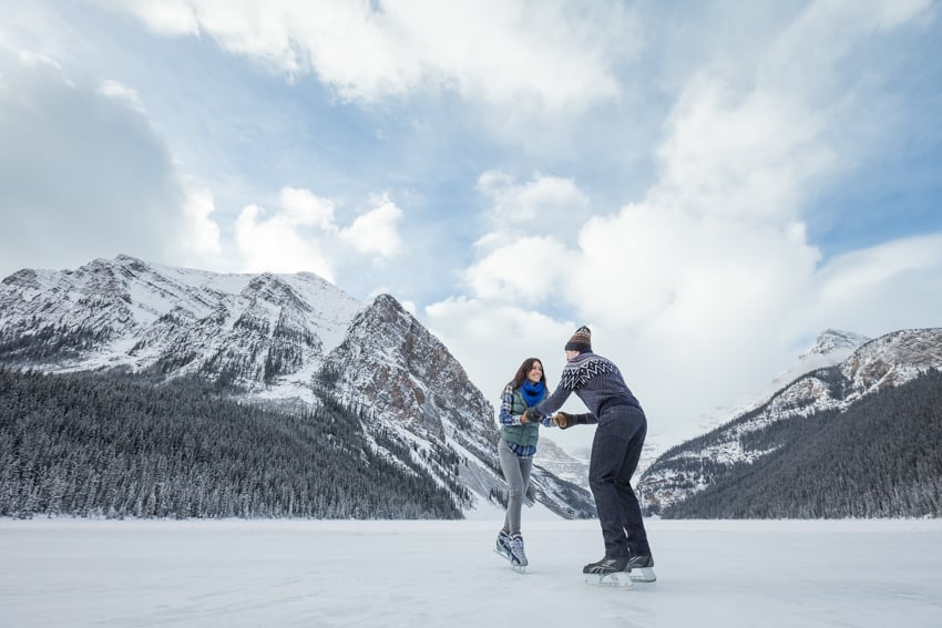 A couple ice skating in nature with beautiful mountains in the background, photo by Gerard Yunker.