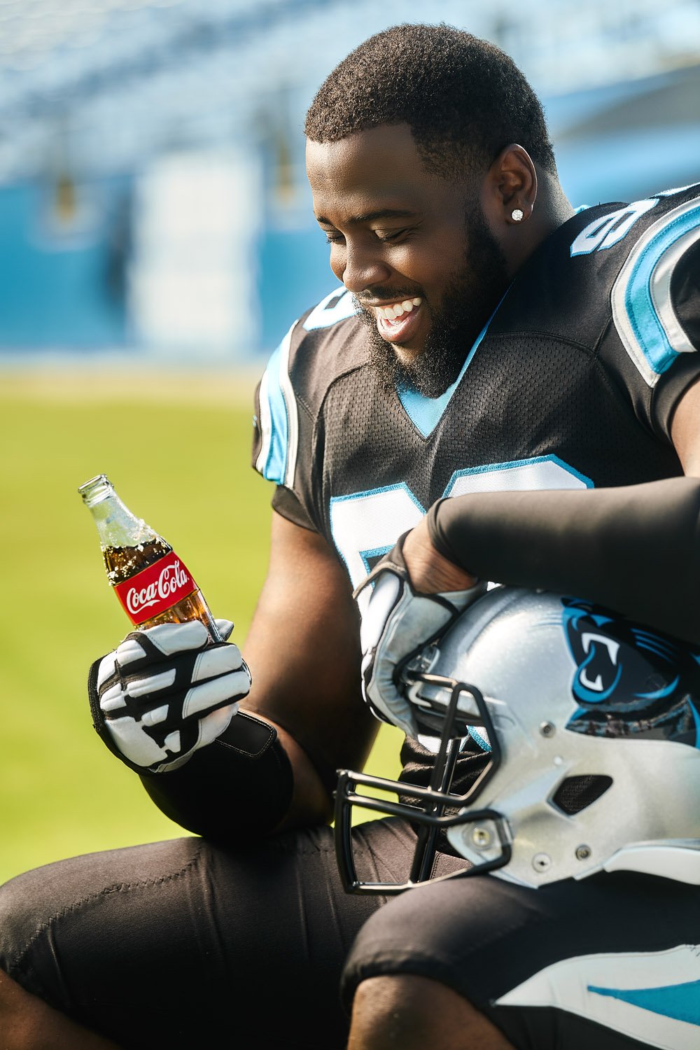 A Carolina Panthers football player looking affectionately at an ice-cold glass bottle of Coca-Cola