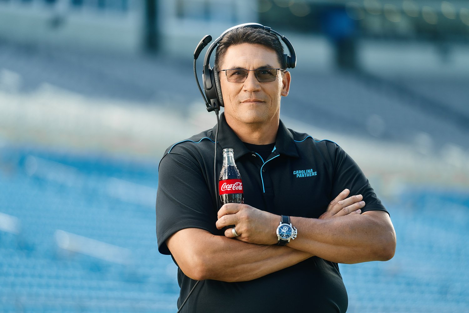 A portrait of Carolina Panthers coach holding a bottle of Coca-Cola