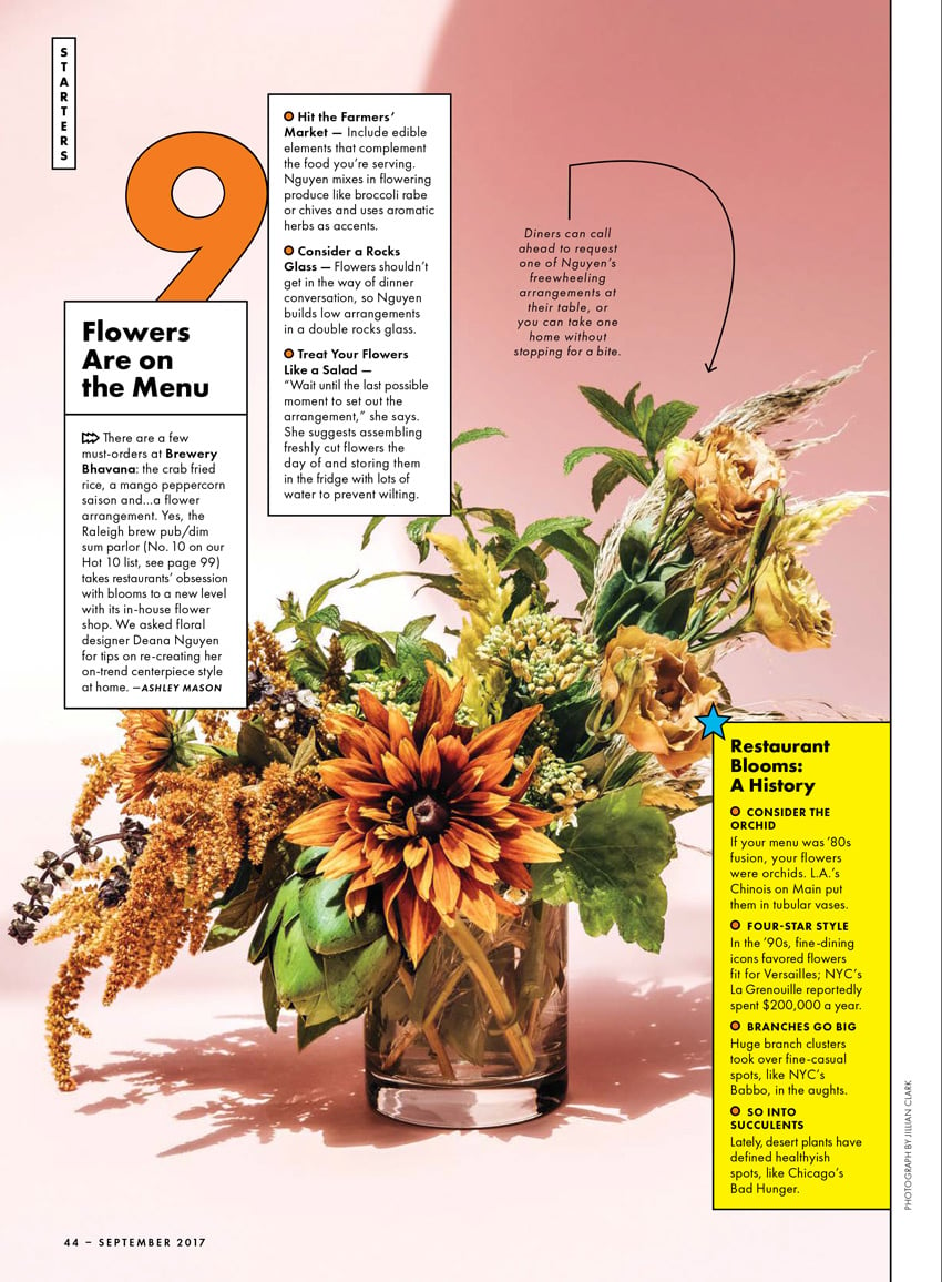 A tear sheet from Bon Appétit featuring Jillian Clark's photo of a cylindrical clear glass vase filled with orange and yellow flowers against a light pink background.