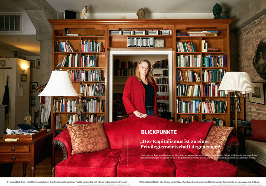 Tear sheet for Wirtschaftwoche featuring Kat Schleicher's portrait of economist Dierdre McCloskey in a living room. She is centered behind a red velvet couch and wearing a red sweater, and she looks directly at the camera.
