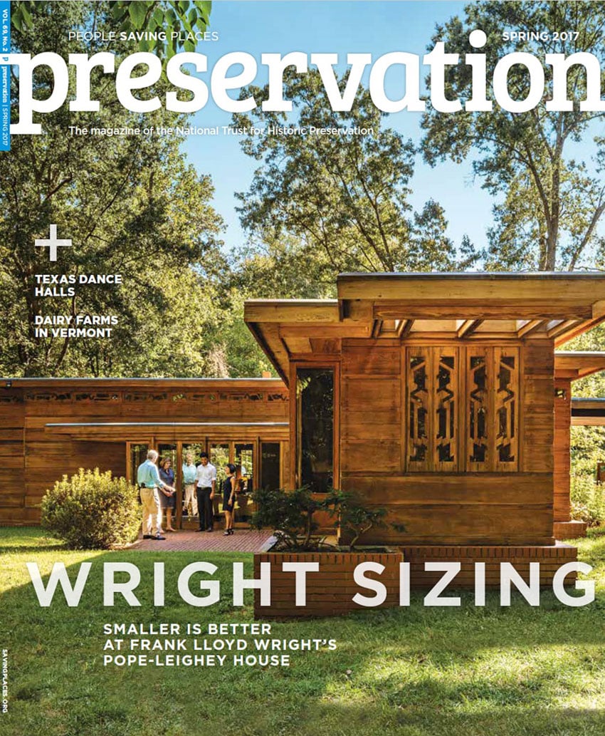 Preservation Magazine's cover featuring Lincoln Barbour's photo of Frank Lloyd Wright's Pope-Leighey House. The house is a single story building made of warm-toned wood. There are trees in the background and a handful of people convening on the patio.
