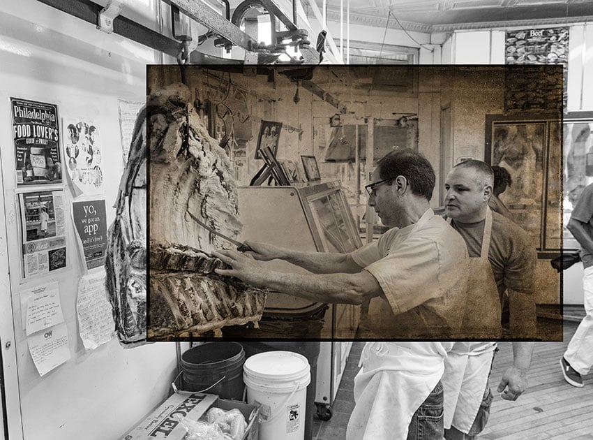 Nashville-based photographer Mark Boughton's photo from Philadelphia's Italian Market. The black and white photo features two men in aprons in a butcher shop communicating over a large segment of meat hanging from the ceiling. 