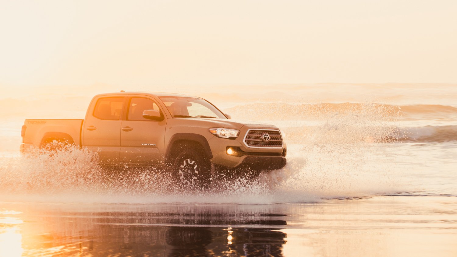 The Toyota Tacoma driving through the shallows of the ocean, photo by Mark Skovorodko.