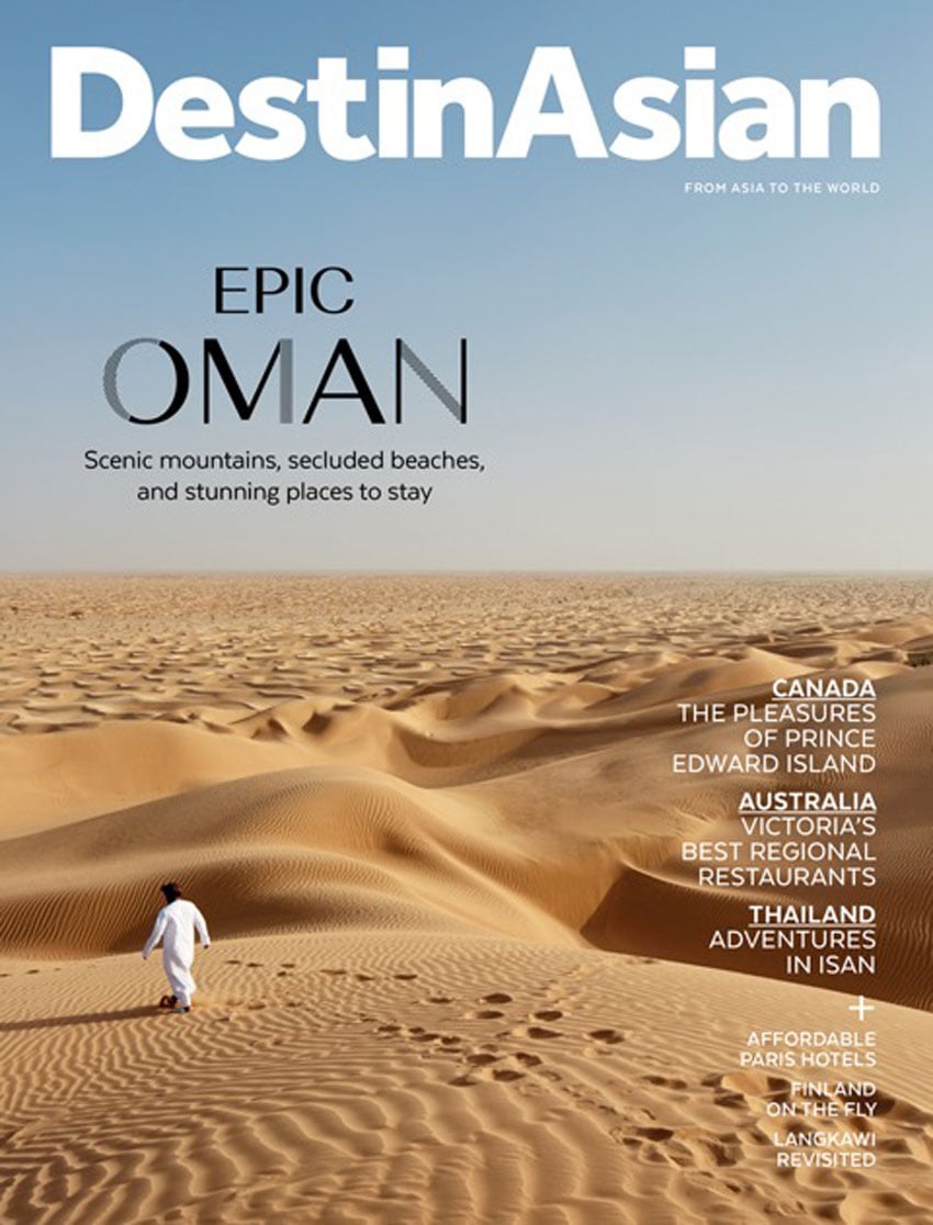 A published tear sheet featuring a solitary figure strolling through the vast Omani desert, photo by Martin Westlake.