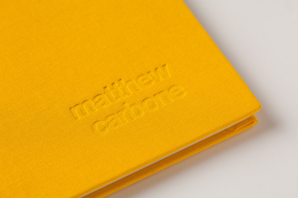 A yellow cover of a book with the photographer's name Matthew Carbone imprinted in the canvas