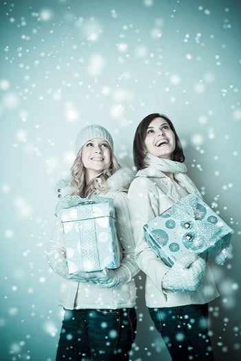 Photo by Robert Karpa of two women holding presents in the snow.
