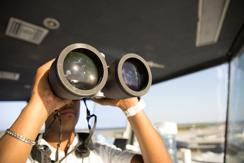 A man looking through binoculars, photo by Roberto Muñoz.
