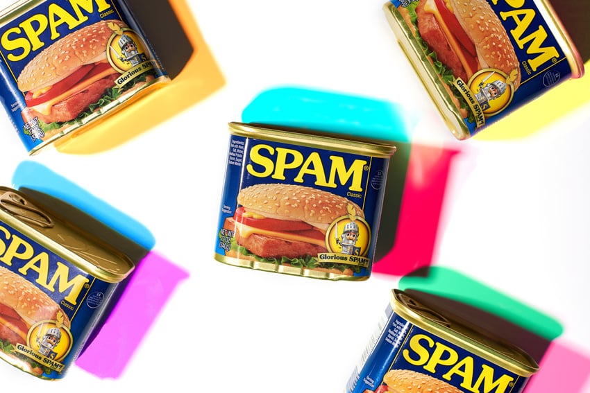Photographer Shea Evans' photo of 5 tins of Spam strewn about on a white surface. Due to Shea's unique lighting technique, each tin casts different color shadows. 