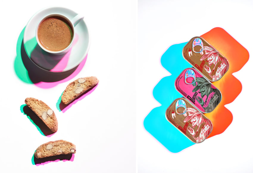 A diptych of photos by photographer Shea Evans. On the left is a photo of a brown drink in a white teacup on a white saucer with 3 small biscotti strewn on the white surface next to it. Each object casts a green and shadow. On the right is a photo of 3 small rectangular tins neatly aligned on an angle that cast a saturated orange shadow to the right and a saturated blue shadow to the left.