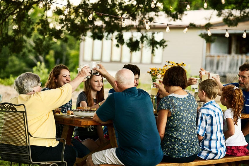 Family joyfully shares a meal amidst the lush beauty of the garden and raise their glasses in a joyful toast, photo by Starboard & Port.