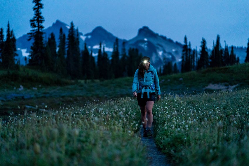 A woman hiking thorough a meadow at dusk, photo by Stephen Matera.