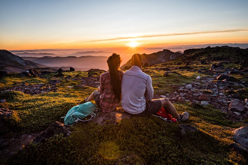 A couple watching a sunset on top of a mossy hill, photo by Stephen Matera.