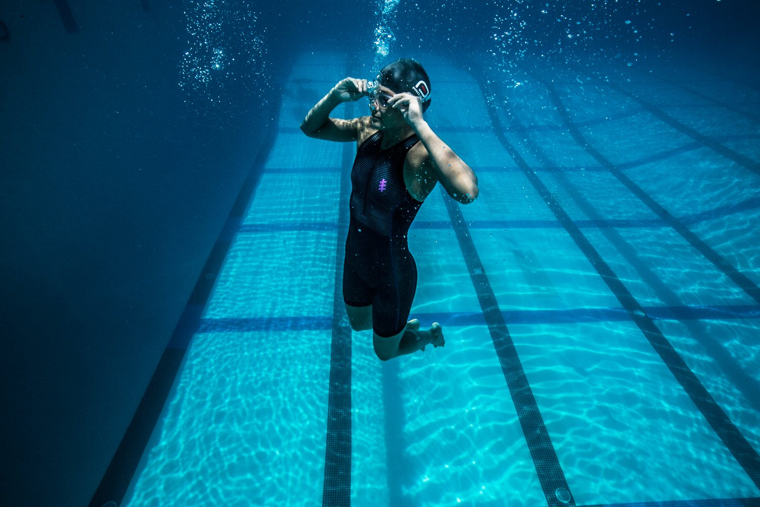 swimmer adjusting goggles underwater, photography by kristyna archer