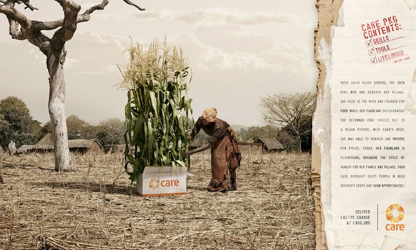 A tear sheet for Care by Tom Cwenar. The tear sheet features a photo of a woman with dark brown skin wearing a wrap skirt and head wrap leaning over a cardboard Care box that appears to have stalks of corn growing out of it. There is an interesting looking dead tree to the left and a collection of buildings with thatched roofs in the background.