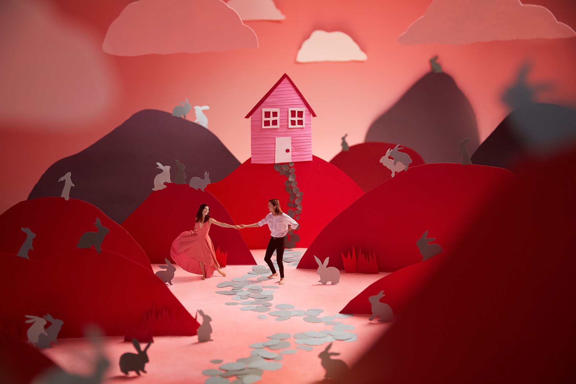 Man and woman dance amid red hills and bunnies made from construction paper shot by Patrick Heageny for Paper Thin