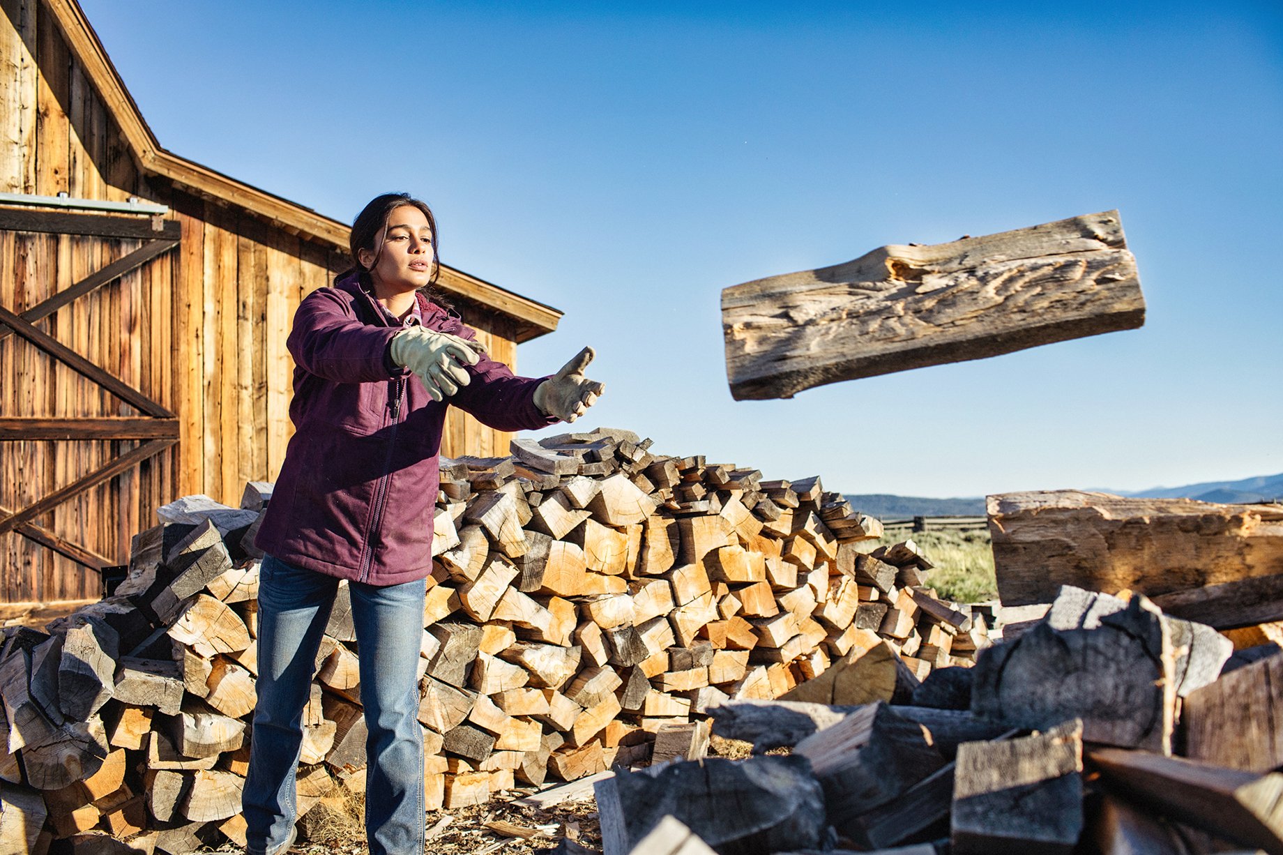 Woman tosses chopped wood onto pile shot by Hillary Maybery for Ariat
