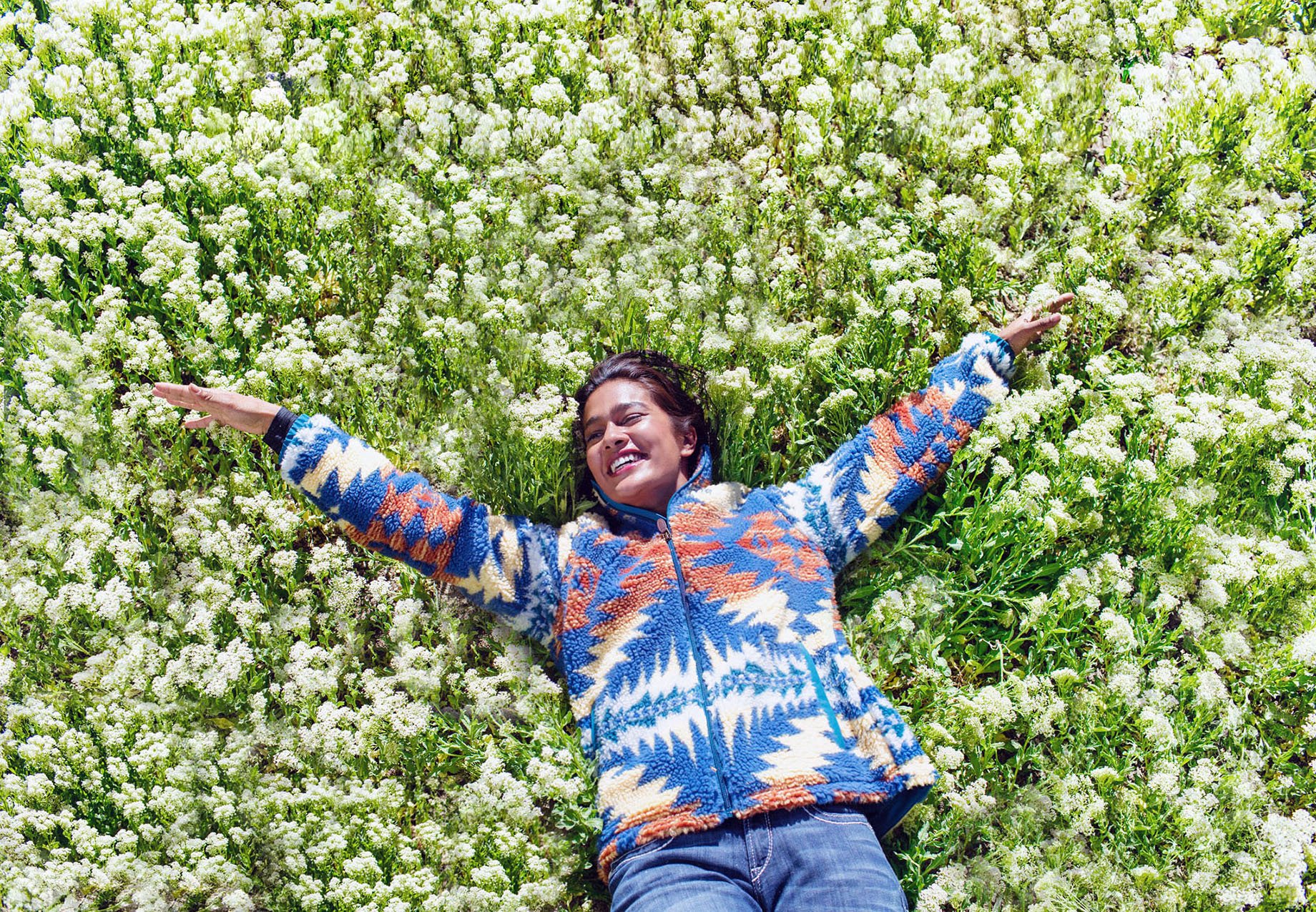 Woman lays in flower field shot by Hillary Maybery for Ariat