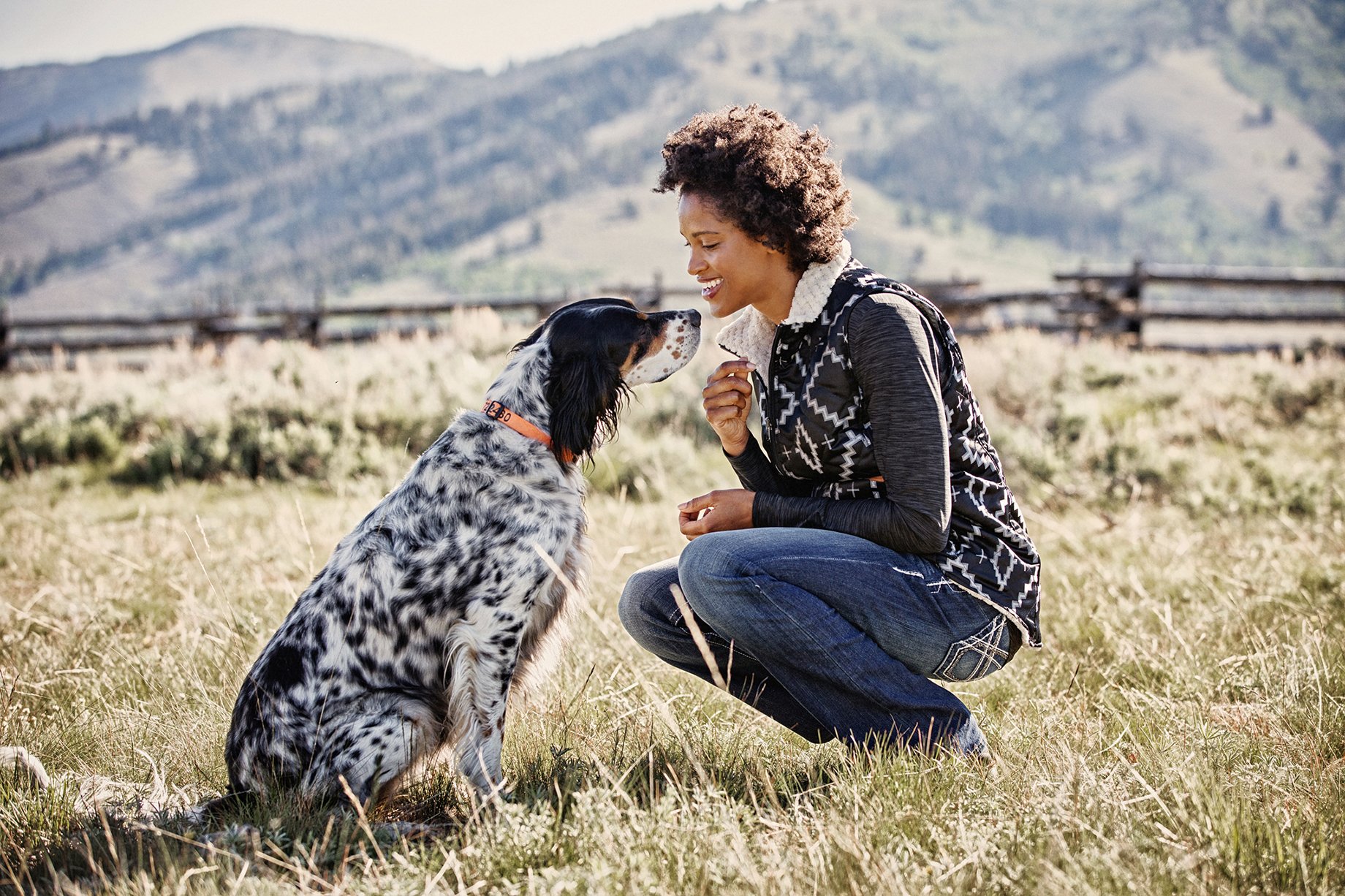 Woman looks at dog in farm field shot by Hillary Maybery for Ariat