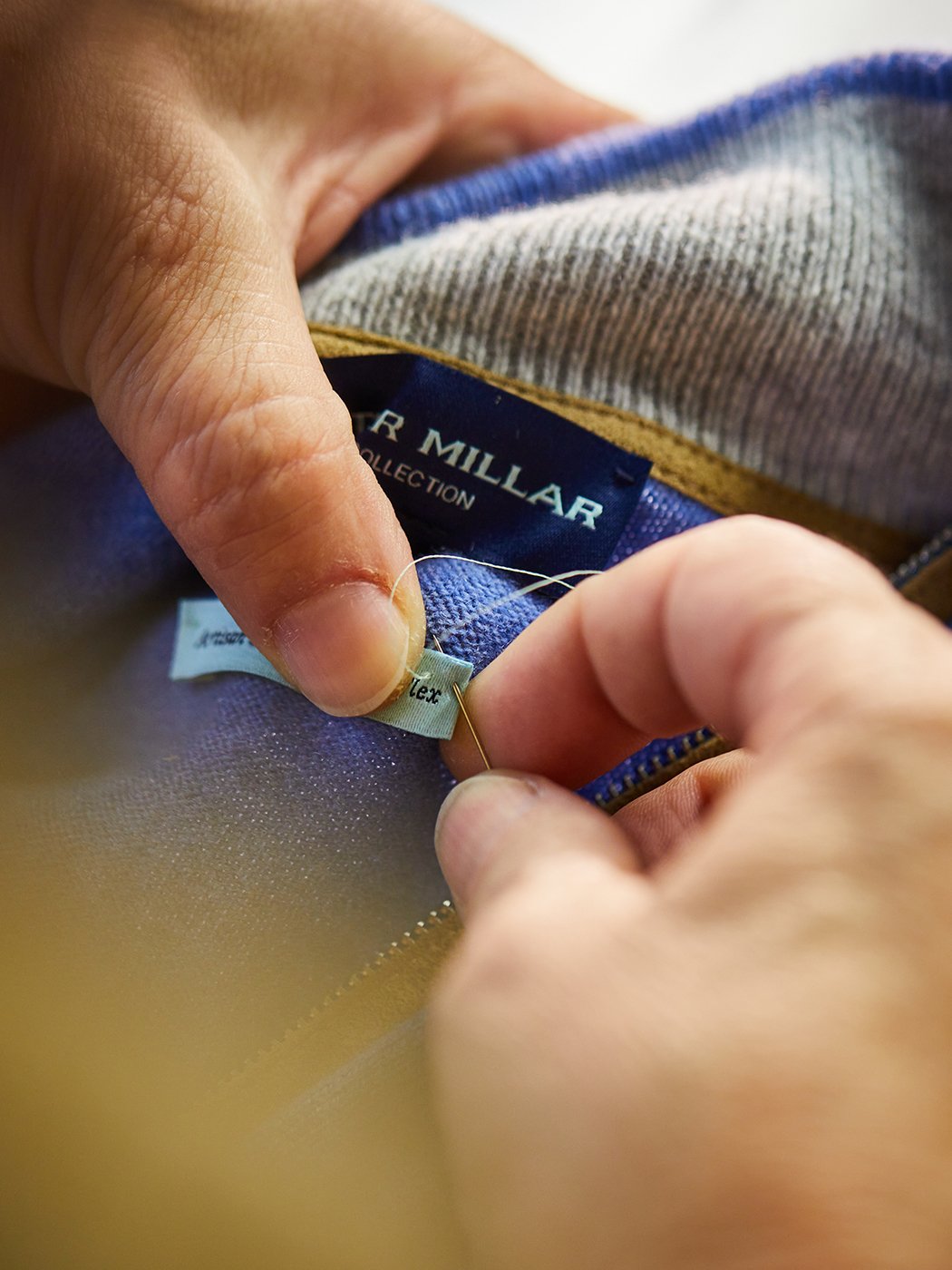 Worker stitching Peter Millar label onto garment at Albion Knitting Co. factory shot by Jackson Ray Petty 