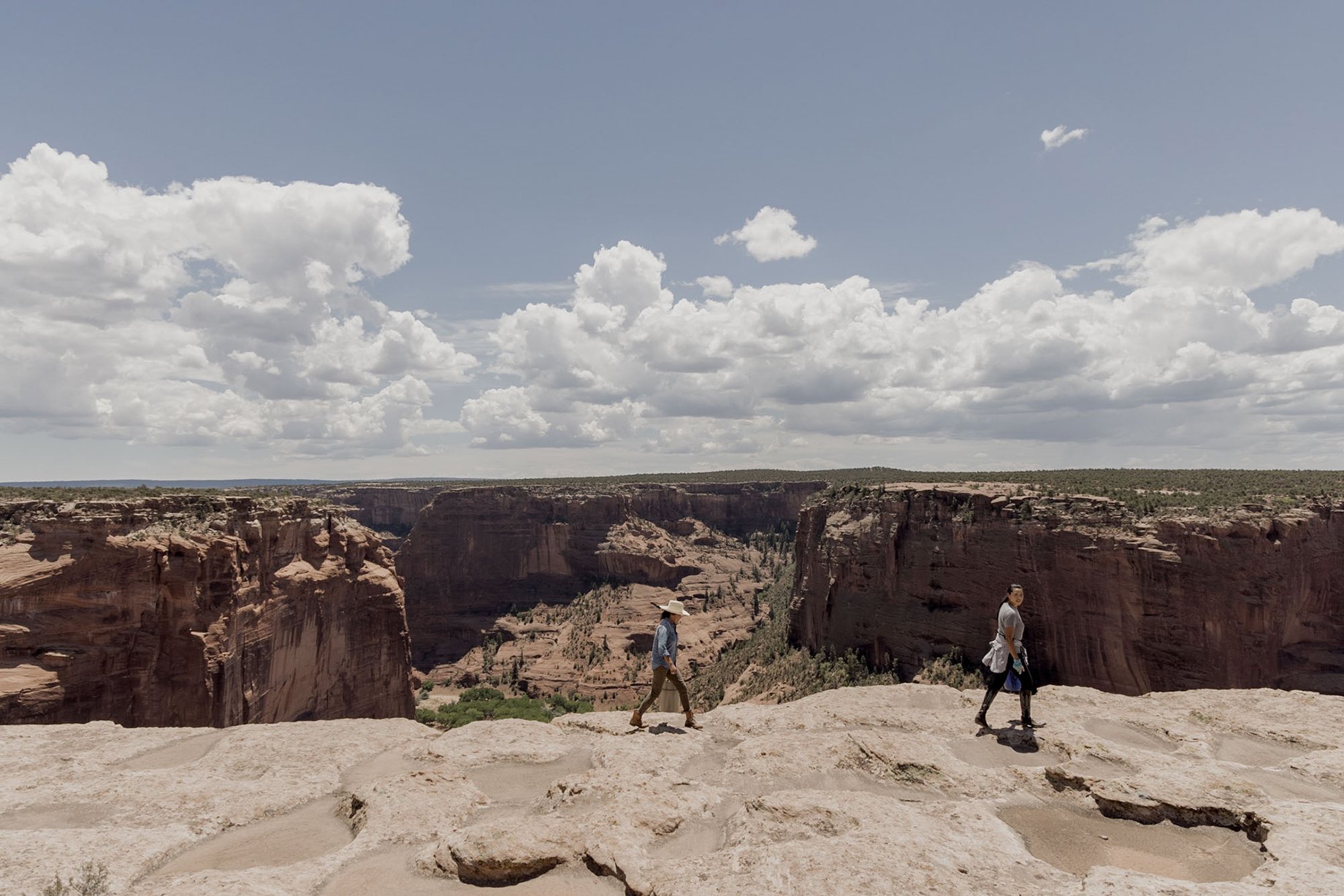 Missy Begay and Shyla Sheppard walking along the rim of Canyon De Chelly shot by Minesh Bacarina for Outside Magazine