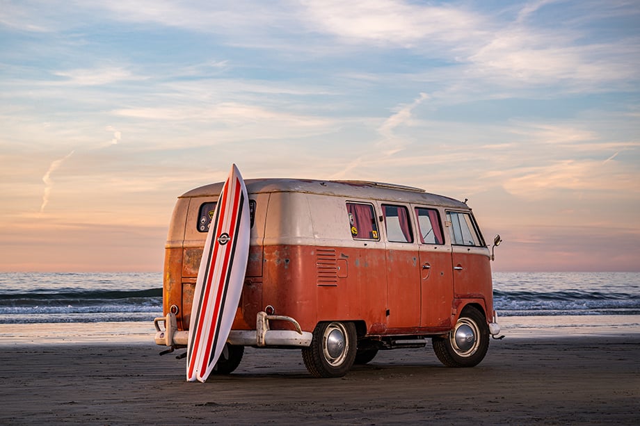 Tim Bessell's custom surfboard rests on an original VW bus on the beach. 
