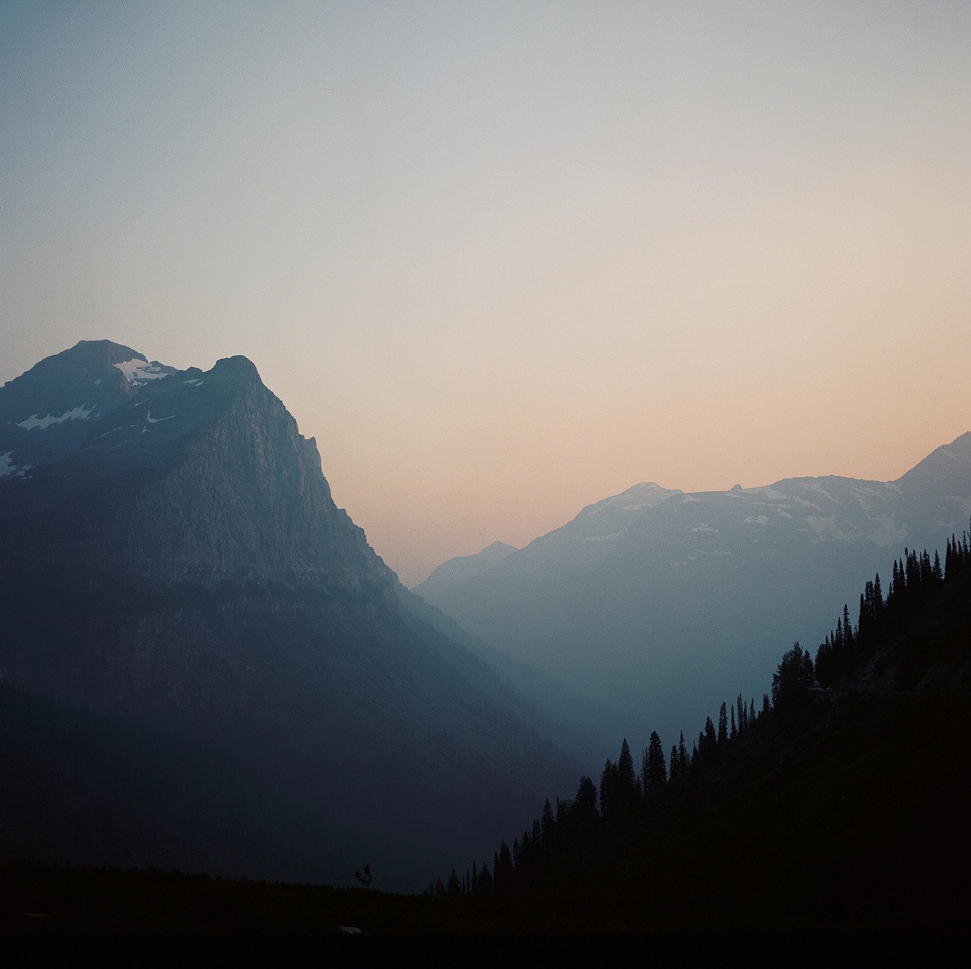 A hazy sunset over snow capped mountains in Montana shot by Abigail Bobo for First Opportunity Bank